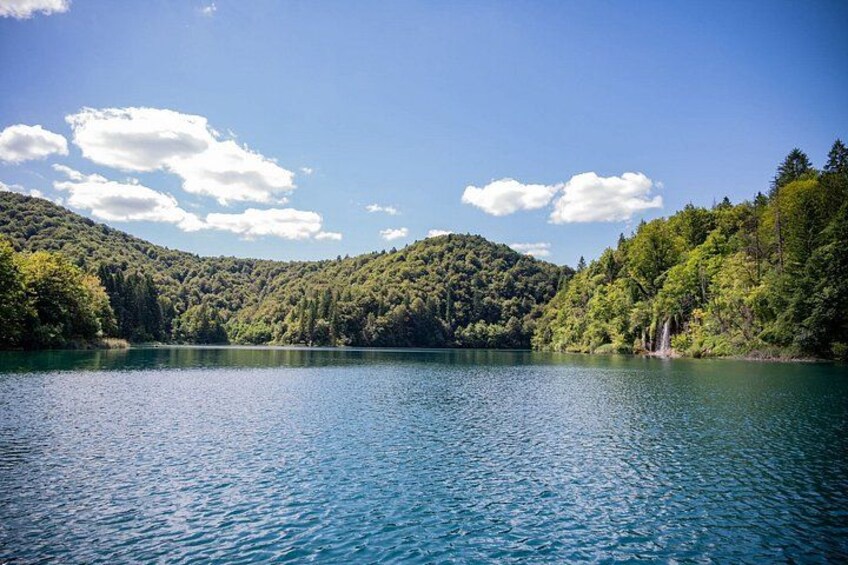A calm lake surrounded by forested hills under a clear sky. 4
