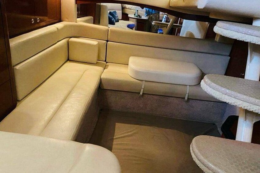 Interior de barco con zona de estar acolchada, rascador para gatos y una pequeña mesa. 4