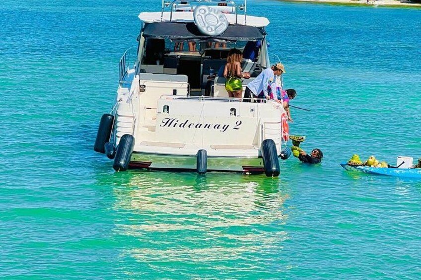 Un barco llamado 'Hidcay 2' en aguas turquesas con personas a bordo y un bote pequeño cerca. 2