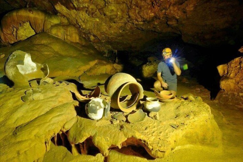 Una cueva con estalactitas y una persona observando un cráneo. 5