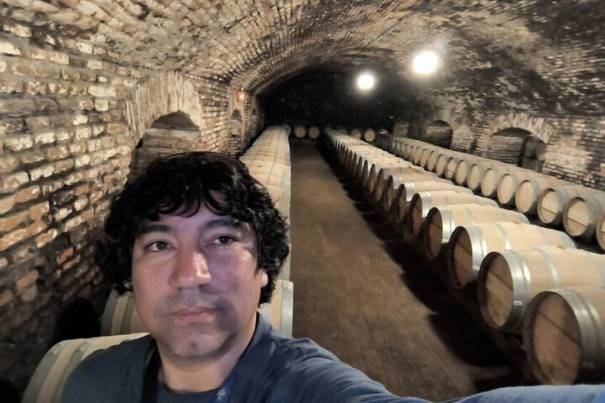 A wine cellar with stone walls and rows of wooden barrels. 4
