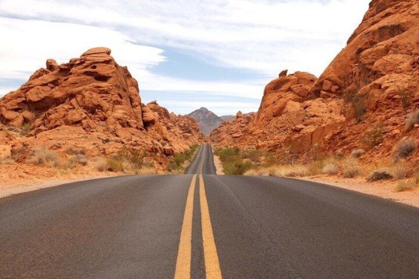 A road flanked by red rock formations under a clear sky. 1
