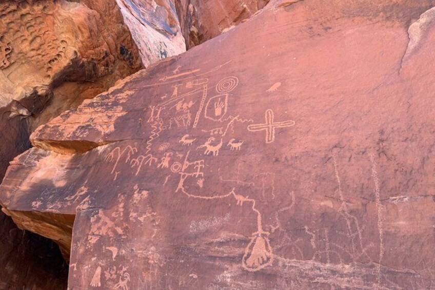 A red rock with ancient petroglyphs including a cross and animal figures. 3
