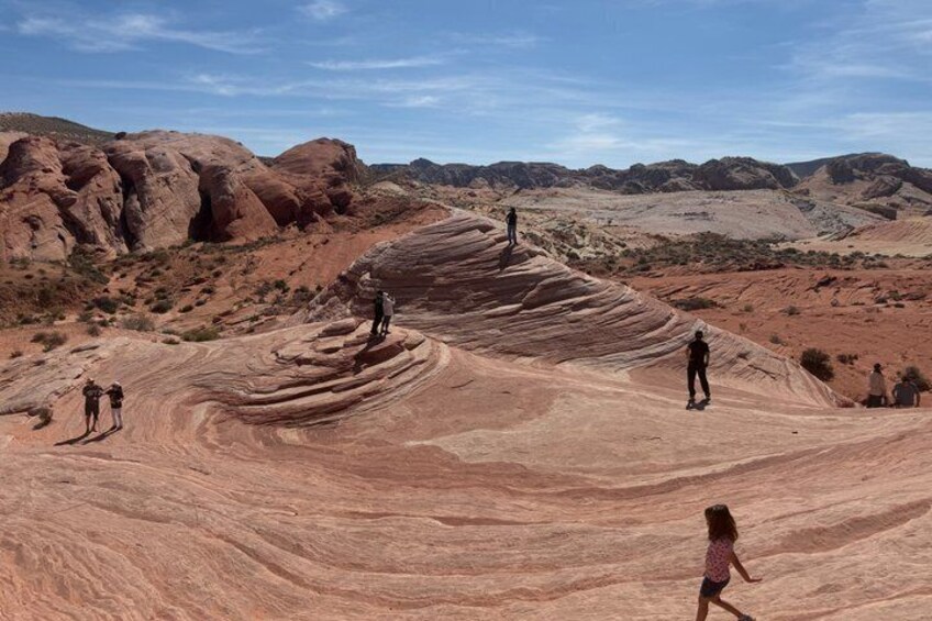 A desert landscape with red rock formations and people hiking. 5