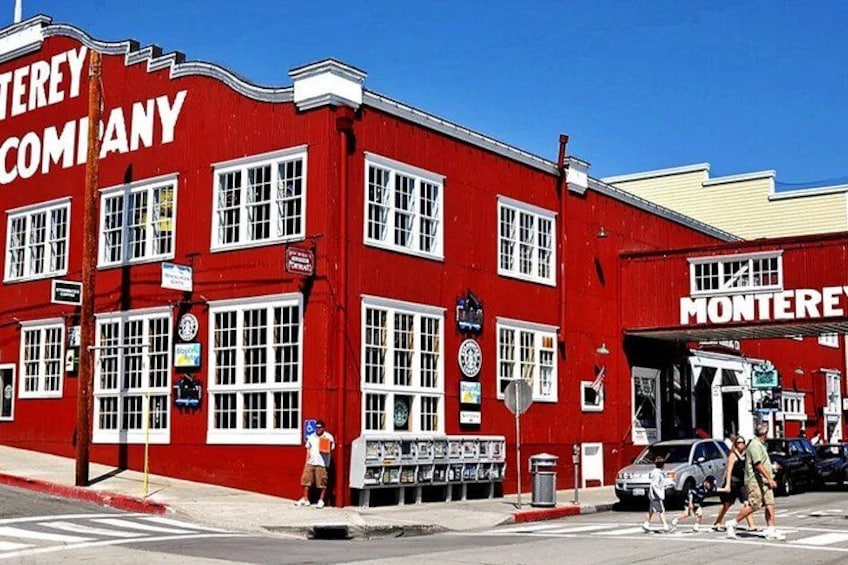 A red building with 'Monterey Company' signage, a street corner, a pedestrian crossing, and a parked car. 3