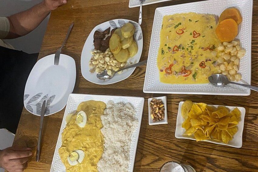 Een houten tafel met diverse gerechten, waaronder rijst, eieren, bonen en een geel gerecht met groenten. 5