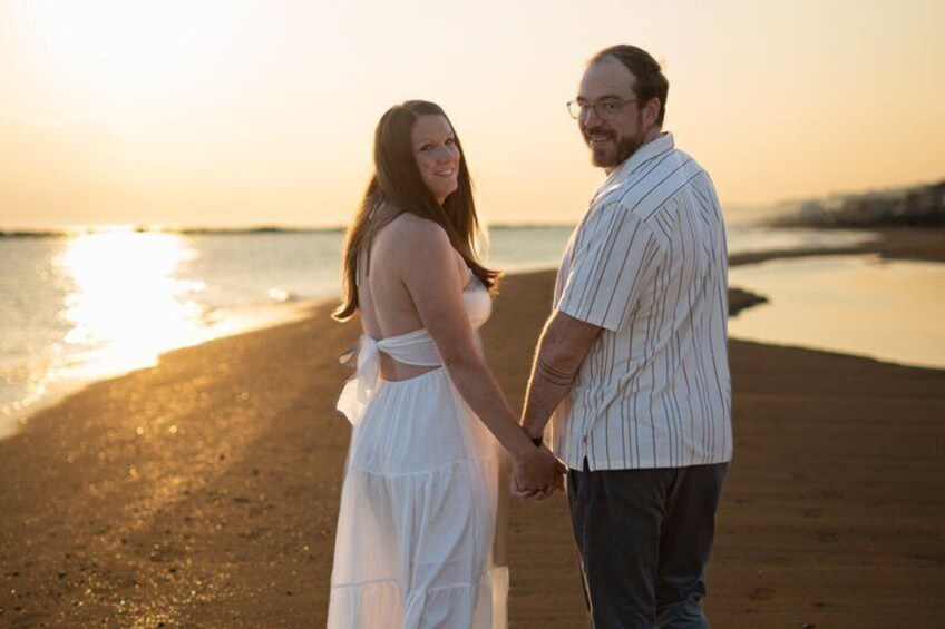 Un couple se tenant la main sur une plage au coucher du soleil. 3