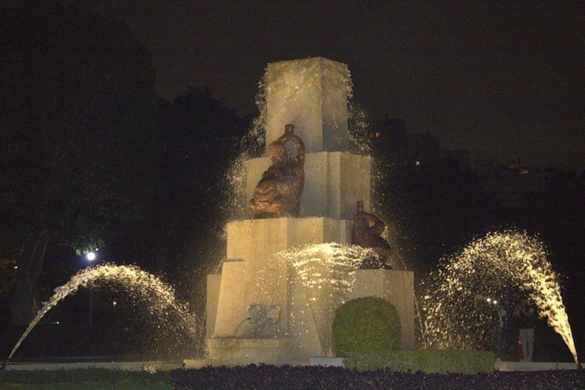 A night-time illuminated fountain with statues and water jets. 4