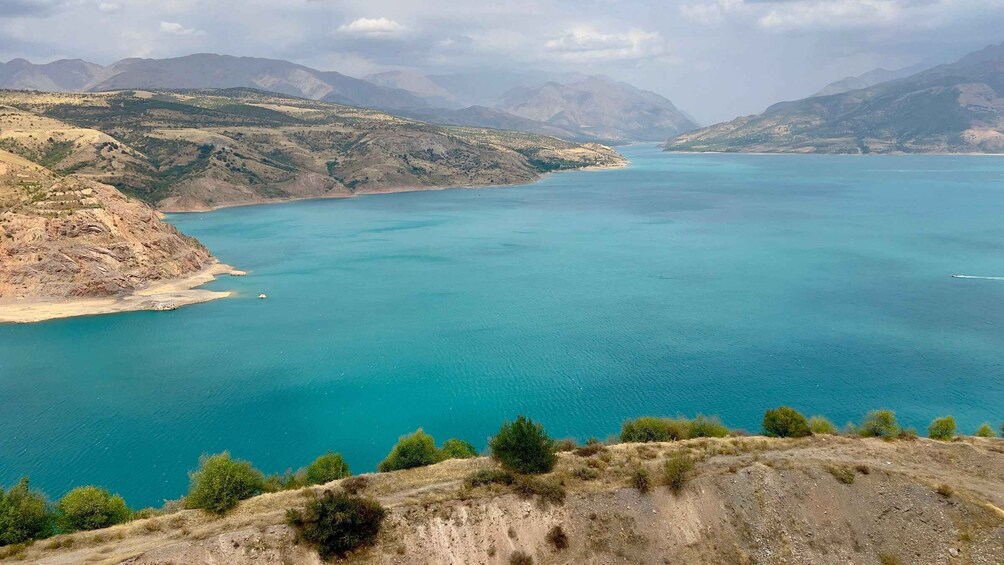 A coastal landscape with a large body of water, hills, and sparse vegetation. 4