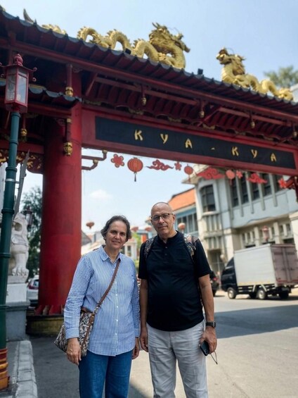 Two people standing in front of a traditional gate with the inscription 'KYAKAYA'. 5