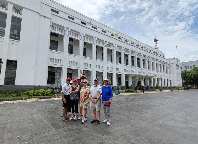 A group of people standing in front of a large white building with columns and a clock tower. 1