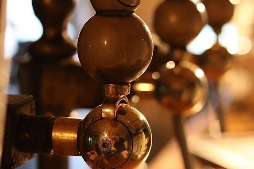 A close-up of a brass bell with a reflective surface, part of a larger bell tower structure. 4