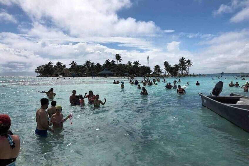 Ein belebter Strand mit Schwimmern und einem Boot im Wasser. 2