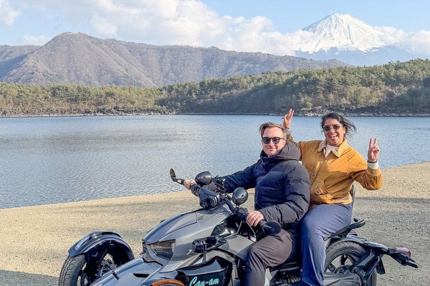 Dos personas en una motocicleta, con un lago y montañas al fondo. 4
