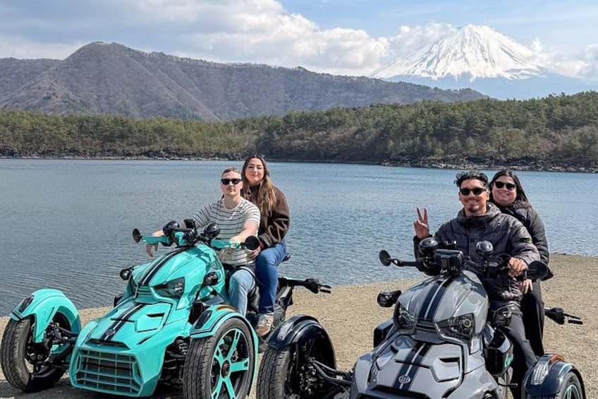 Un cuatrimoto turquesa, una persona haciendo el gesto de la paz y una montaña nevada al fondo. 2