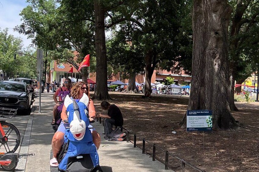 A park with trees, a paved path, and people riding bicycles. 3