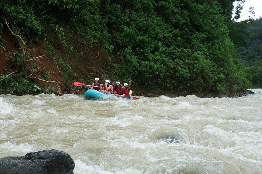 A group of people rafting down a river surrounded by dense greenery. 2