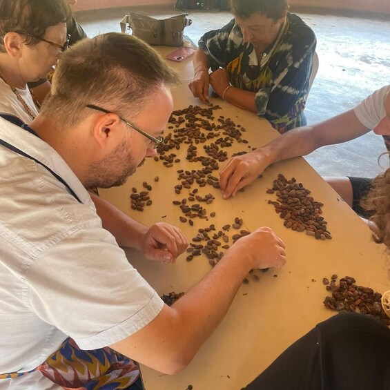 People seated around a table with coffee beans scattered on it. 4