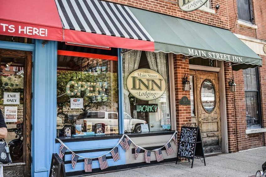 Main Street Inn met een rode luifel, een 'Beschikbaar'-bord en Amerikaanse vlaggen in het raam. 4