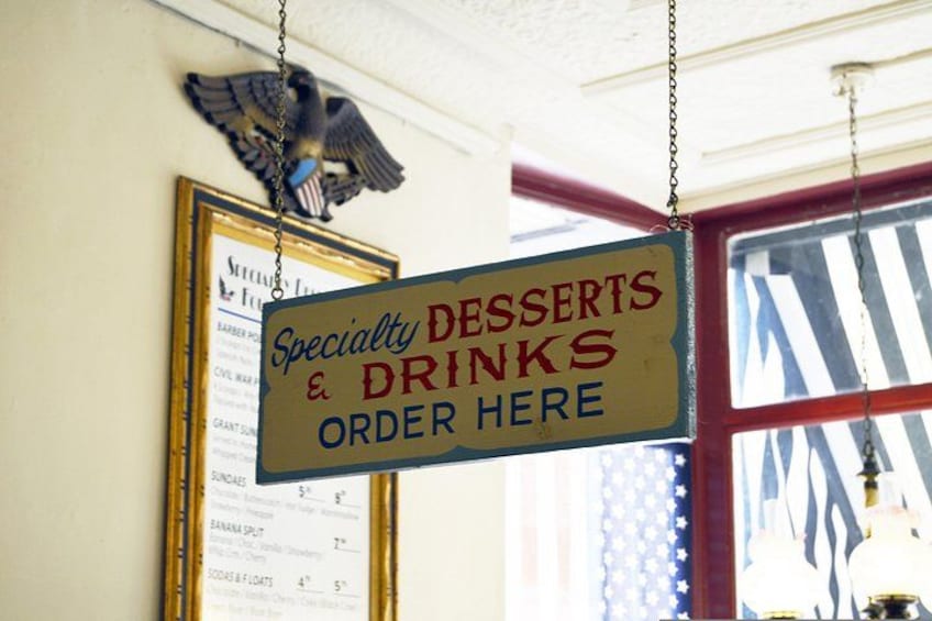 Een bord met de tekst over speciale desserts en drankjes, een ingelijst menu en een arend decoratie. 2