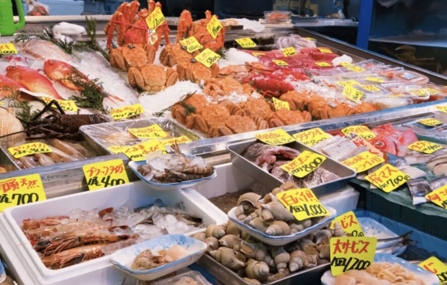 A seafood market with various fish and shellfish on ice, labeled with prices. 5