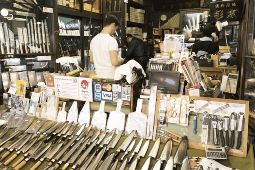 A store with various knives on display and a man working behind the counter. 4