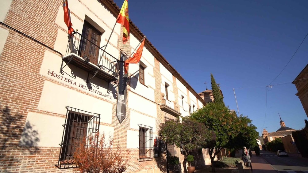 A building with a sign reading 'Hosteria del Estudiante' and flags hanging from the balcony. 3