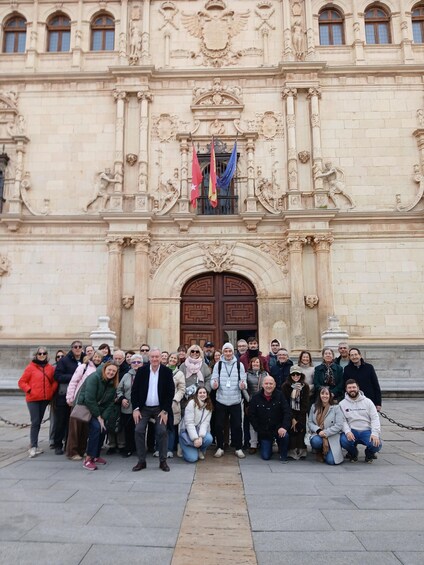 A group of people standing in front of a building with ornate carvings and a large wooden door. 4