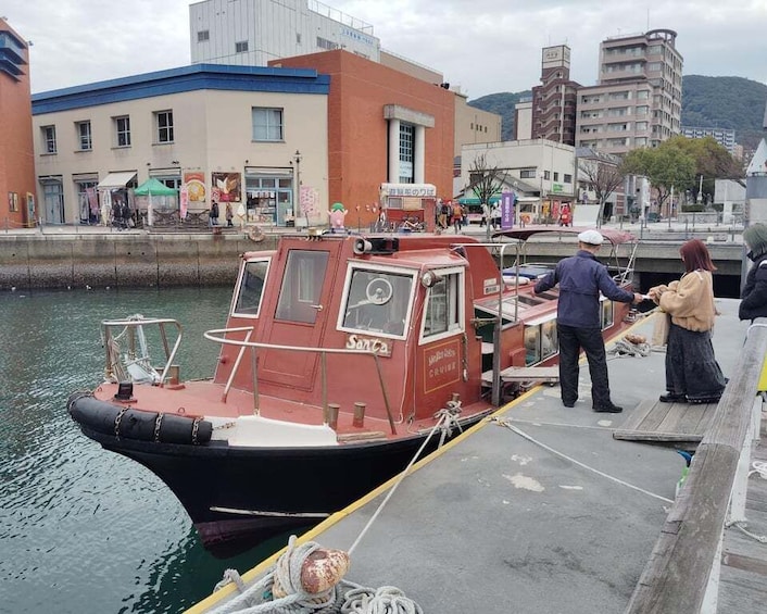 A red boat docked at a pier with people standing nearby. 1
