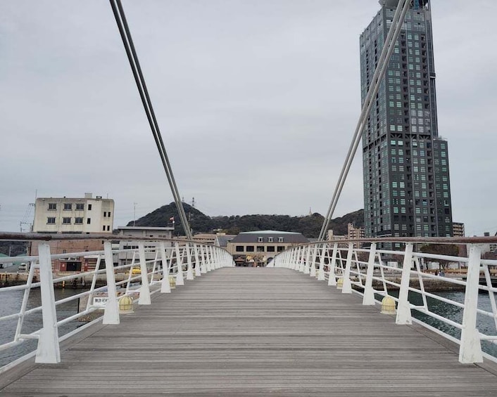 A wooden pedestrian bridge with white railings, leading to a modern building with a dome. 2