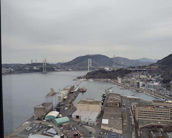 A coastal city with a prominent bridge, industrial buildings, and a mountainous backdrop. 4