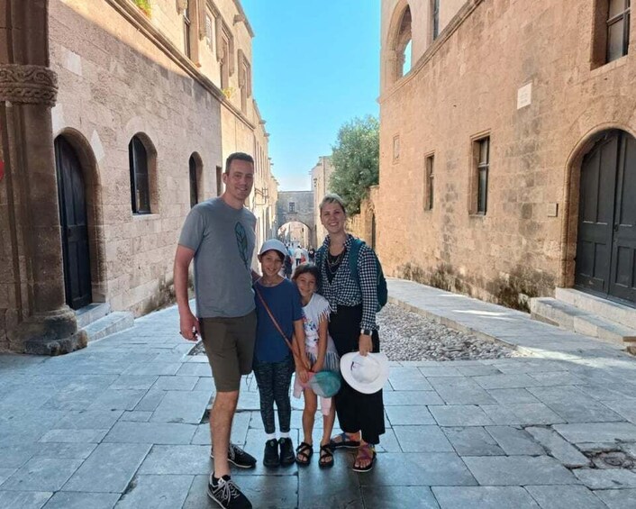 A family standing in a narrow street with historic buildings on either side. 4