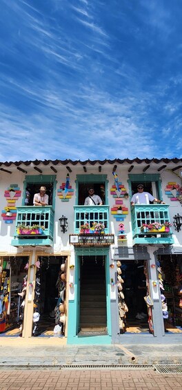 A colorful building with balconies, a sign reading 'ARTESANIAS DE MI PUEBLO,' and various items displayed outside. 2