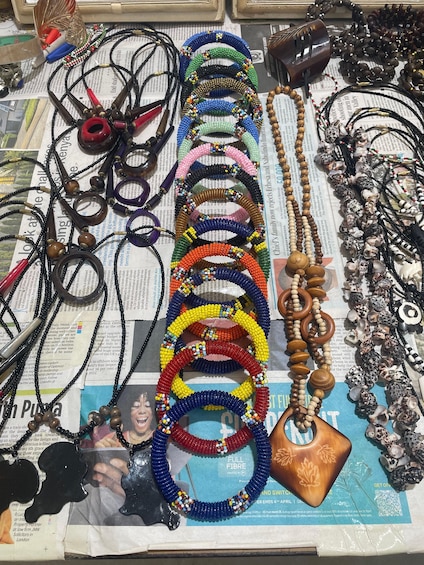 A variety of beaded necklaces and bracelets laid out on a newspaper-covered surface. 5