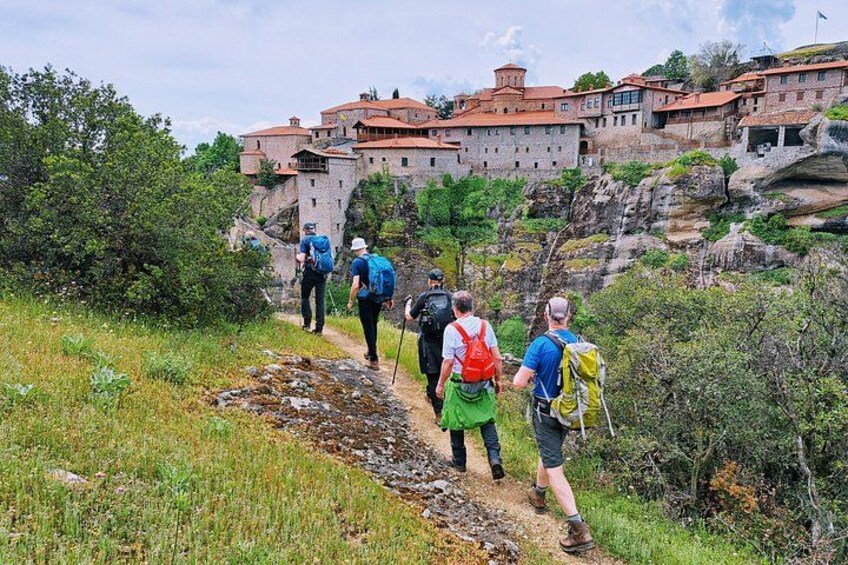 Hikers on a rocky trail with a historic building in the background. 1