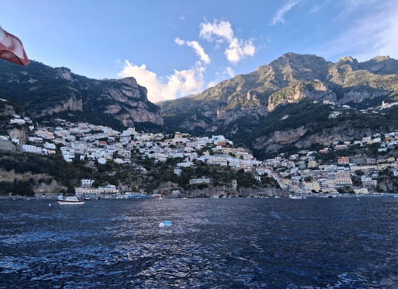 A coastal town with white buildings nestled in a mountainous landscape. 1