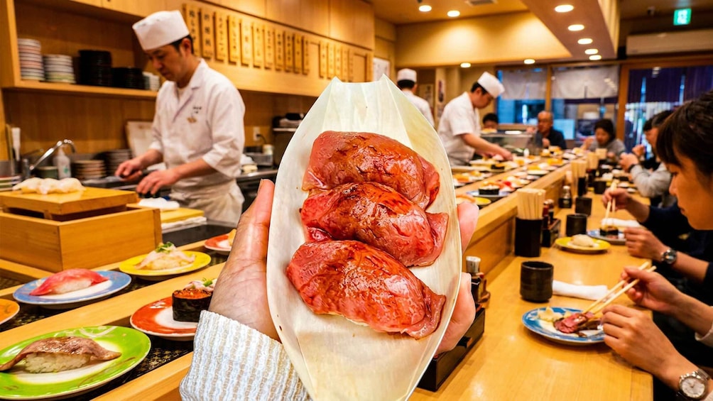 A person holding a tray with three grilled sausages in a restaurant. 2