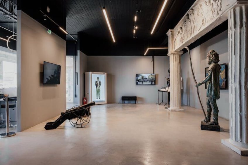 An art gallery with sculptures, a piano, and a large painting on the wall. 1