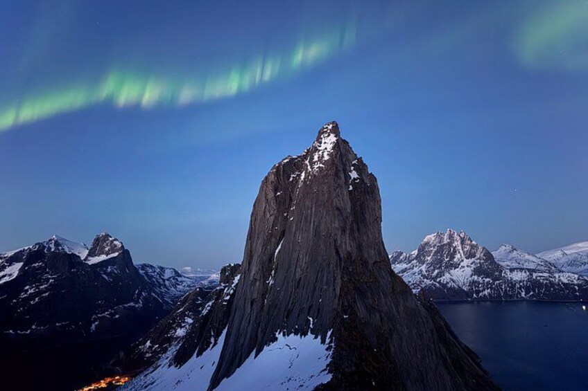 Un sommet montagneux enneigé, un fjord et des aurores boréales. 3
