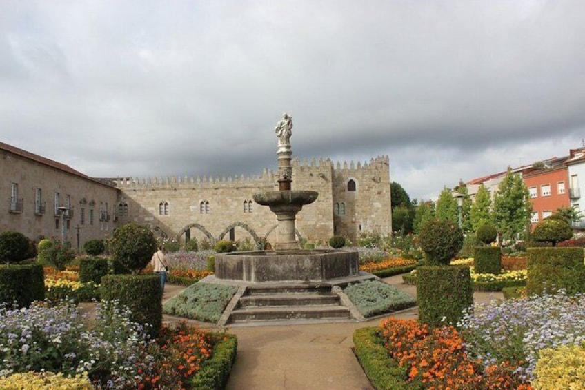 Een historisch kasteel met een centrale fontein, omringd door goed onderhouden tuinen en een verhard pad. 4