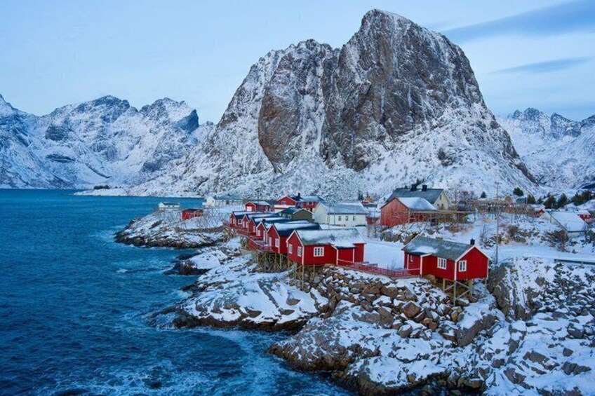 A coastal village with red houses, a large mountain, and a fjord. 4