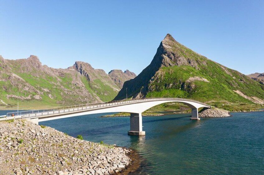 A white bridge over a calm river with mountains in the background. 3