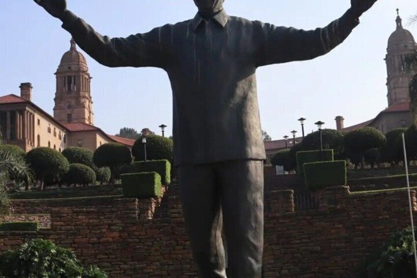 Eine Statue mit ausgestreckten Armen, eine Steinmauer und im Hintergrund ein Gebäude mit einer Kuppel. 4