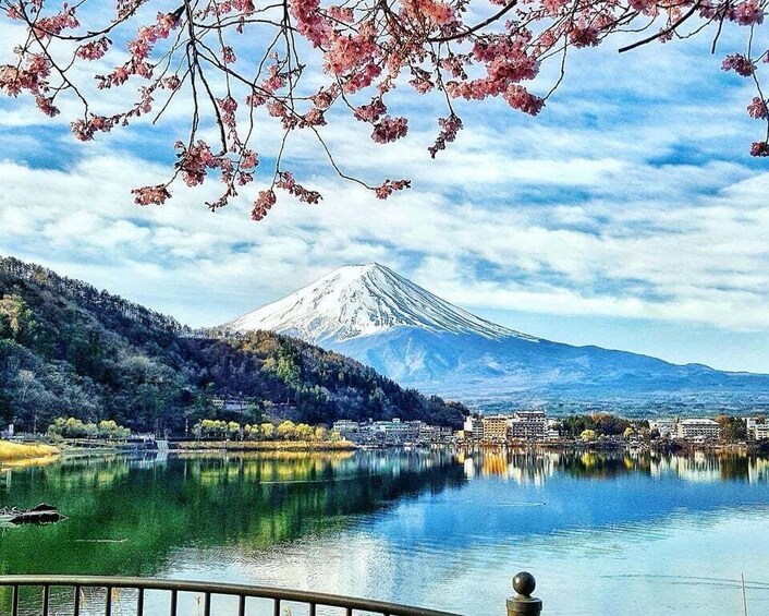 A mountain with a snow-capped peak, a calm lake, and a bridge in the foreground. 5