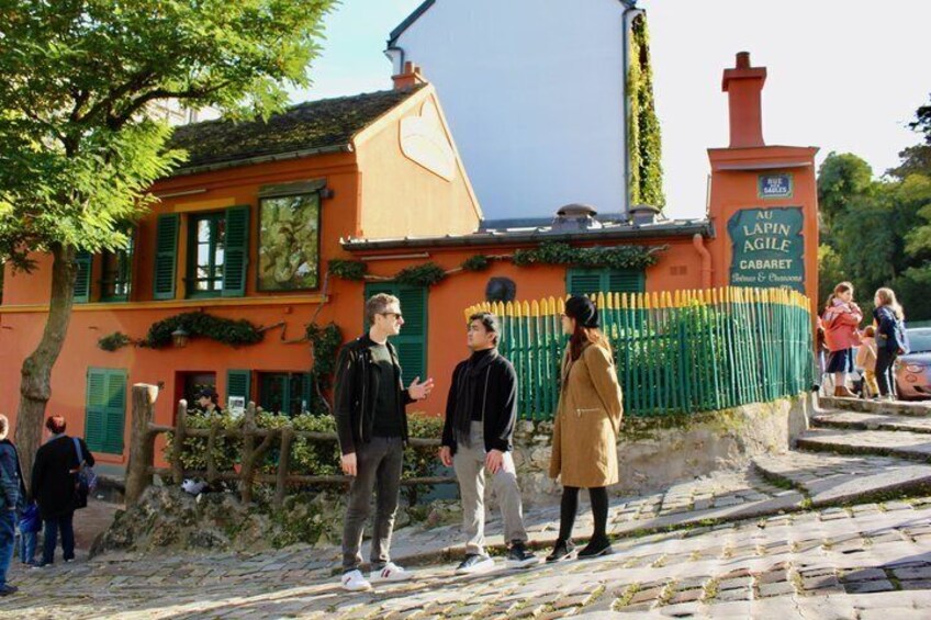 Un edificio con un cartello che recita 'Au Lapin Agile' e una strada acciottolata. 4
