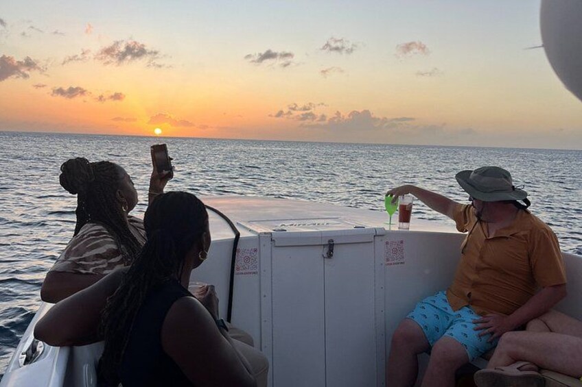 A sunset over the ocean with people on a boat. 2