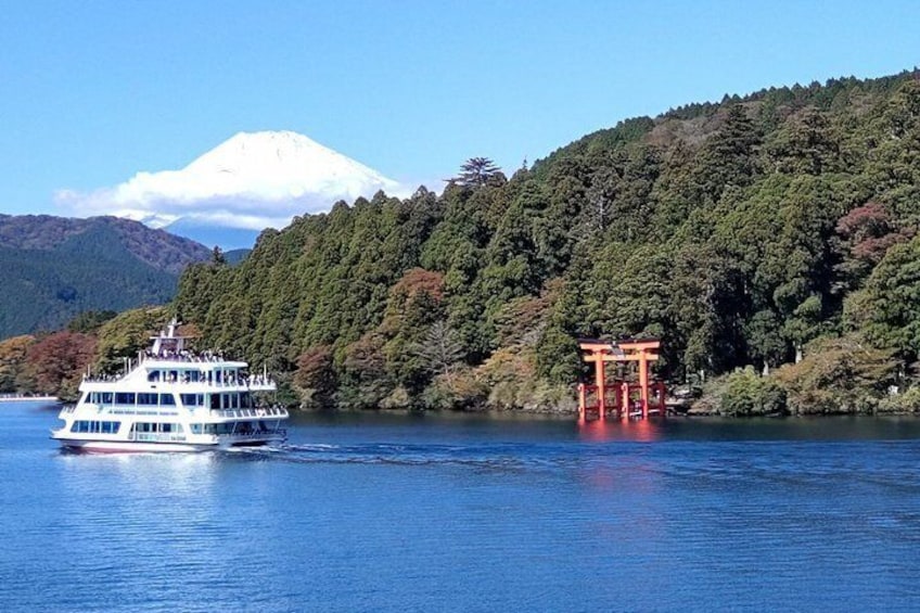 Un bote blanco sobre el agua, un torii rojo y una montaña nevada. 1