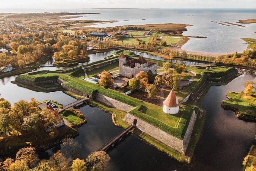 A fortified complex with a central tower, surrounded by water and greenery. 1