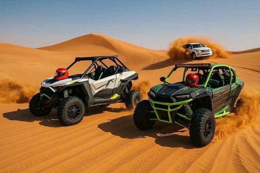 Two off-road vehicles on a sandy terrain with dunes in the background. 2