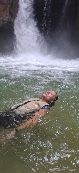 A person floating in a body of water with a waterfall in the background. 4